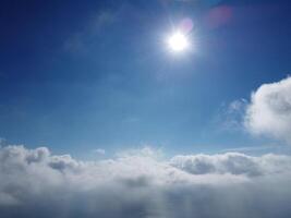 Aerial view. The drone flies over foggy and fluffy clouds. Blue sky sun and sea fog. Abstract aerial nature summer ocean sunset sea and sky background. Vacation, travel and holiday concept photo