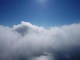 Aerial view. The drone flies over foggy and fluffy clouds. Blue sky sun and sea fog. Abstract aerial nature summer ocean sunset sea and sky background. Vacation, travel and holiday concept photo