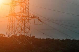 High voltage electric distribution network at sunset. Power transmission lines on supports with ceramic insulators and transformers at large electrical distribution substation photo