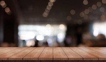 Empty wooden table top with lights bokeh on blur restaurant background photo