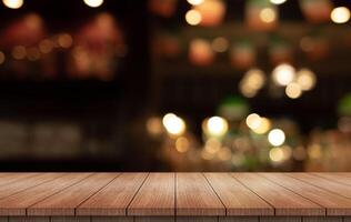 Empty wooden table top with lights bokeh on blur restaurant background photo
