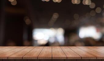 Empty wooden table top with lights bokeh on blur restaurant background photo