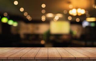 Empty wooden table top with lights bokeh on blur restaurant background photo