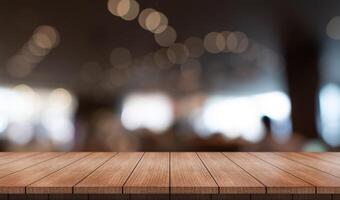 Empty wooden table top with lights bokeh on blur restaurant background photo