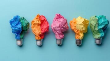 Colorful paper crumples atop light bulbs on a blue background, symbolizing creativity and innovation in design. photo