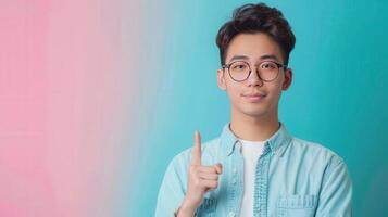 A young man in glasses points upward against a colorful background, conveying a sense of positivity and inspiration. photo