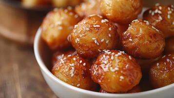 Golden brown sesame balls served in a bowl, showcasing a crispy texture and enticing aroma, perfect for snacking or festive occasions. photo