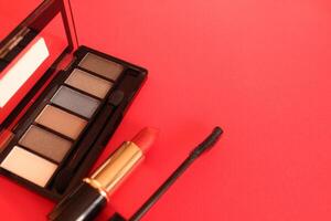 Eye shadow mascara lipstick on a red background with space for text. Make-up and make-up photo