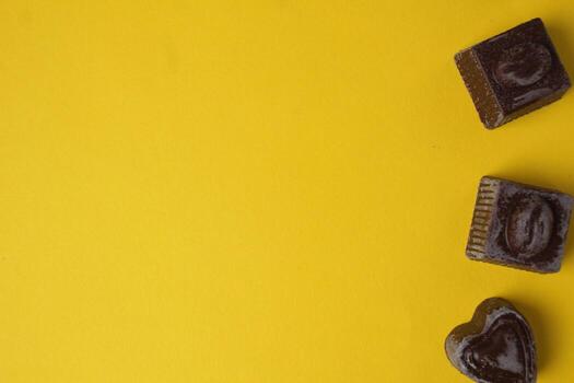 Chocolate candies on a yellow background top view with space for text and copyspace. Food Background photo