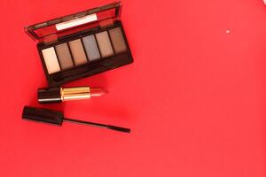 eye shadow mascara lipstick. Makeup tools on a red background with space for text coisspace upper angle photo