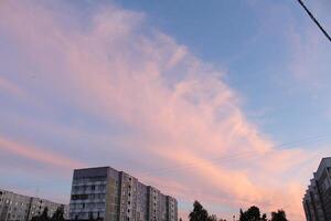 Clouds above the house. Summer sunset in the city on the houses. City sunset photo