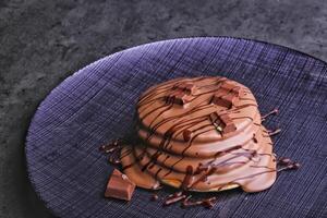 Kinder Chocolate Pancake Stack drizzled with rich chocolate sauce and topped with chocolate chunks served in plate isolated on napkin side view of dessert photo