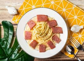 Creamy Bacon Pasta Noodles in plate with fork and spoon isolated on napkin top view of taiwan food on table photo