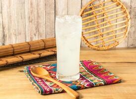 Refreshing Iced Lemonade, Lemon plum or lemon soda filled with ice cubes served in tall glass isolated on napkin side view on wooden table of taiwan drink photo
