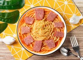 Ham, bacon and Tomato Spaghetti in plate with fork and spoon isolated on napkin top view of taiwan food on table photo
