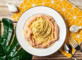 Creamy Chicken Pasta Noodles with Parmesan Cheese in plate with fork and spoon isolated on napkin top view of taiwan food on table photo