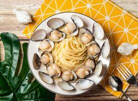 Creamy Clam Spaghetti with Fresh Clams pasta in plate with fork and spoon isolated on napkin top view of taiwan food on table photo
