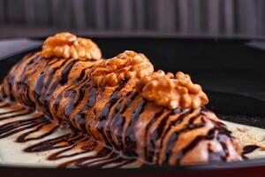 Decadent Chocolate Walnut Cinnabon Roll with Drizzled Sauce served in plate isolated on dark background closeup side view of dessert photo