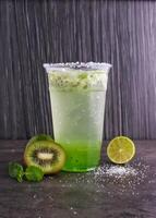 Refreshing Kiwi Mojito made with fresh kiwi slices, lime juice, mint leaves, and sparkling water served in glass isolated on background side view of healthy drink photo