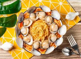 Clam Spaghetti with Tomato sauce, Fresh Clams pasta in plate with fork and spoon isolated on napkin top view of taiwan food on table photo
