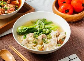 Wenzhou wonton noodles soup with green onion in bowl isolated on napkin side view on table taiwan food photo
