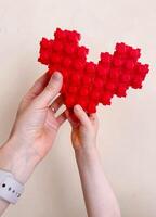 Family photo, hands of mother and child holding a heart made from a toy construction set. photo