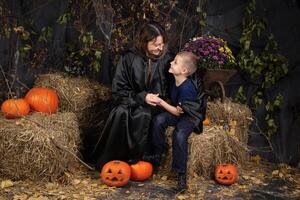 Happy mother and son playing during Halloween. cheerful family in carnival costumes in a room painted with pumpkins for the holiday of Halloween. Cheerful children playing with pumpkins and sweets photo