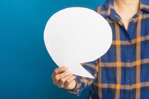 Question mark speech bubble concept. Midsection of a man holding a blank paper while standing with blue background in the studio. Space for text. Talking and message for social media concepts ideas photo