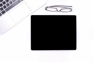 Top view of a blank tablet, laptop and glasses isolated on white background. Space for text. Technology and communication concept photo