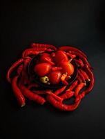 A bowl of red peppers and tomatoes on a black background photo