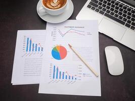 Top view of paperwork, laptop, mouse, and a coffee cup on the desk in the office. Business and strategy concept photo