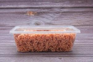 Package for sale of sweet and sour crispy noodles or Mee krob on a wooden table. Side view with copy space for text photo
