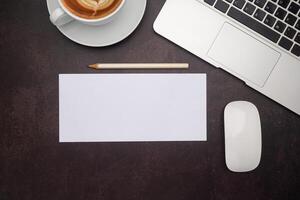 Top view of white paper or envelope and a pencil with a laptop, mouse, and a coffee cup on the desk in the office. Vintage background photo