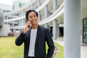 A successful Asian businessman is standing in an outdoor hallway and talking on the phone. photo