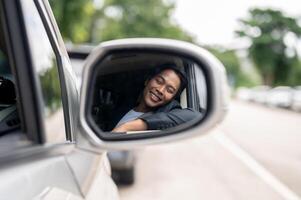 A close-up image of a car's wing mirror with a man in a business suit smiling in the reflection. photo