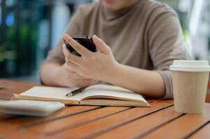 A cropped shot of a woman using her smartphone at a table in a cafe. photo