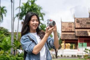 A happy, charming Asian female tourist is enjoying taking a photo and strolling in a Thai temple.