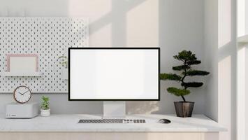 A modern white computer desk features a computer with a white-screen mockup and decor. photo