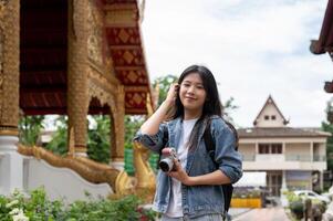 A beautiful Asian female tourist is visiting a Thai temple in Chiang Mai, smiling at the camera. photo