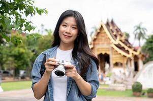 An attractive Asian female traveller is smiling at the camera, visiting Thai temple in Chiang mai. photo