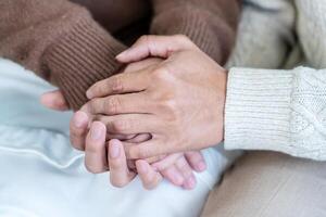 Closeup, couple and holding hands while resting on couch at home, to forgive, love and care with empathy at home. Life partner, helping hand and support of man, woman and hope for kindness photo