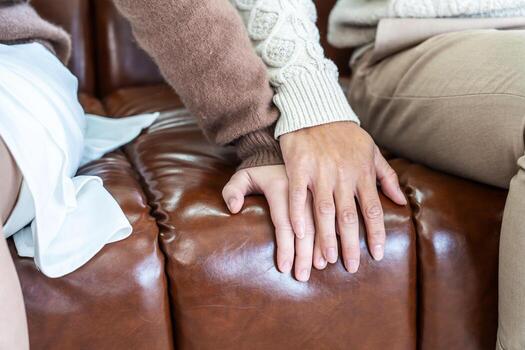 Closeup, couple and holding hands while resting on couch at home, to forgive, love and care with empathy at home. Life partner, helping hand and support of man, woman and hope for kindness photo
