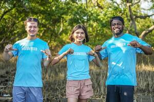 Group of multiethnic volunteers showing the lettering on t-shirts together in partnership teamwork smiling look at the camera in forests, Environmental protection, and ecology concept. photo