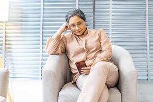 Pleasant senior older lady resting on couch at home, older middle aged female customer holding smartphone using mobile app, texting message, search ecommerce offers on cell phone technology device photo