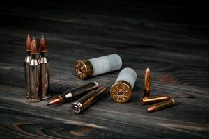 Various types of ammunition on a wooden surface. Cartridges for weapons. Dark back. photo