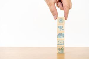 Businessman hand with wood cube block and icon symbol to 5G network high speed mobile internet new age network, mixed media, World wide business photo