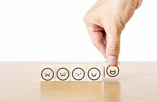 Hand of a businessman chooses a smiley face icon on wood block cube, The best excellent business services rating customer experience, Satisfaction survey concept, Service rating photo
