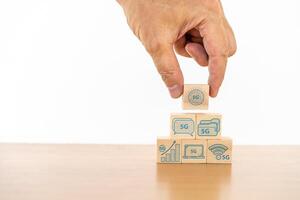Businessman hand with wood cube block and icon symbol to 5G network high speed mobile internet new age network, mixed media, World wide business photo