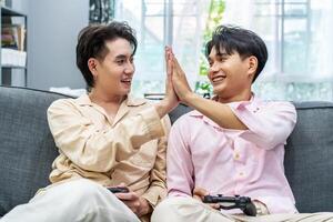 Two young males relax on weekend sit on couch enjoy console game push buttons on controllers, Two Male Players spend free time together play online game photo
