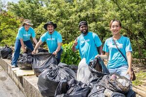 cuatro voluntarios en trabajo mono recoger basura en bosque en el plastico bolsa. de cerca durante acción. limpieza de naturaleza desde desperdiciar. ambiental asistencia. basura colección en bosque foto